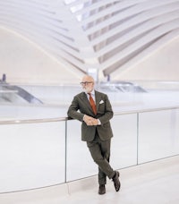 a man in a suit leaning against a railing in a modern building